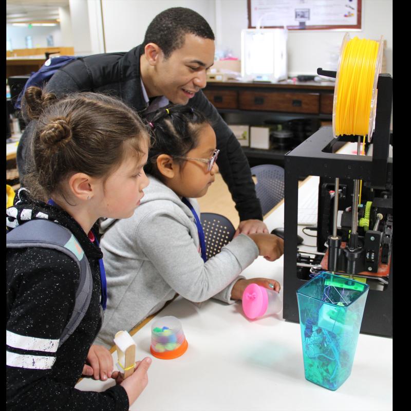 Teacher showing 3D printer to students