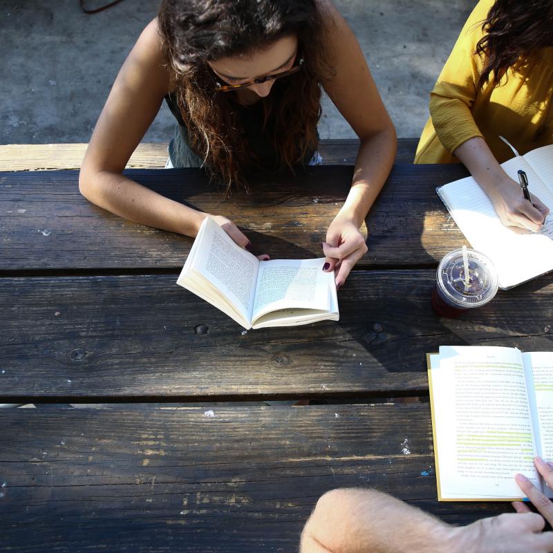 Three students sitting at table reading